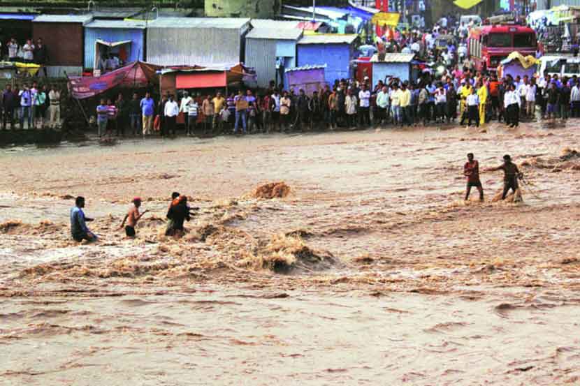 नाशिक येथे गोदाकाठी पाण्यात अडकलेल्यांना बाहेर काढताना स्थानिक तरुण.   (छाया : यतीश भानू)