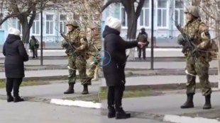 woman offers sunflower seeds to Russian soldier