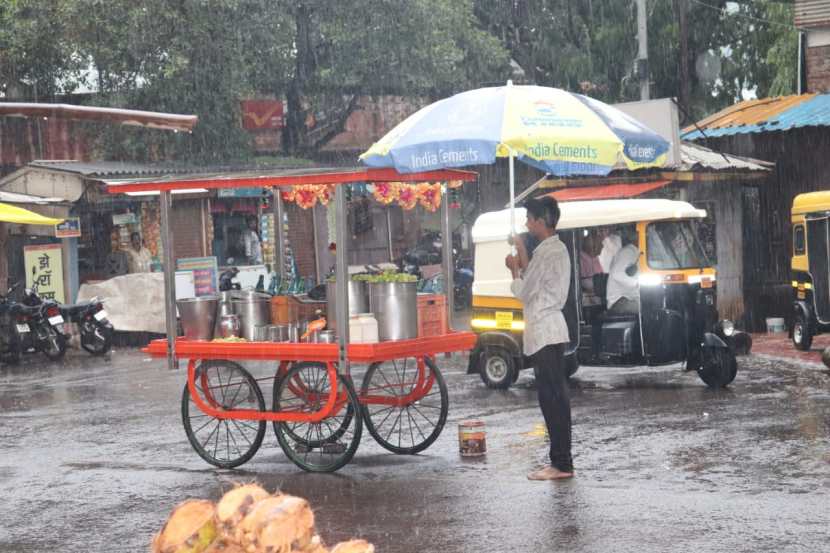 पावसापासून बचाव करण्यासाठी फेरीवाल्याने मोठी छत्री पकडून थांबावे लागले.