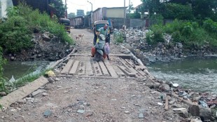 Passengers travel dangerously through the drain in Kopar East in Dombivli