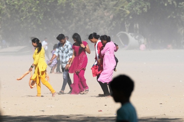 मुंबईतील गिरगाव समुद्रकिनारी धूळ आणि वाळू सर्वत्र पसरली आहे. यामुळे येथून जाणाऱ्या पादचाऱ्यांना धुळीचा त्रास सहन करावा लागत आहे. बिपरजॉय चक्रीवादळामुळे समुद्र खवळला आहे. (एपी फोटो)