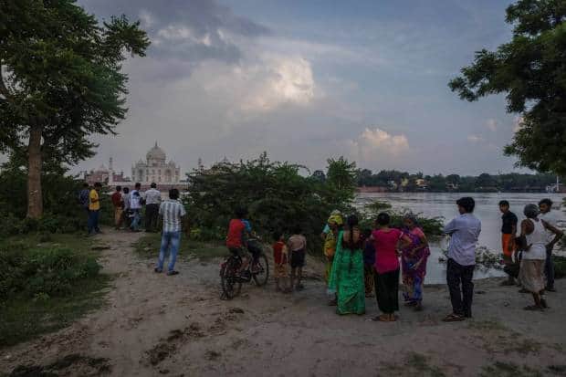 आग्रा येथे मुसळधार पावसामुळे यमुना नदी ओसंडून वाहत असल्याने लोक ऐतिहासिक ताजमहालासमोर पुराच्या पाण्याजवळ उभे आहेत. रॉयटर्स
