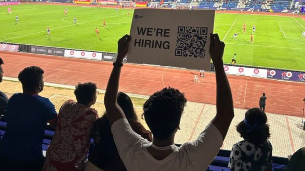 Man holds were hiring placard during football match in Bengaluru Man holds were hiring placard during football match in Bengaluru