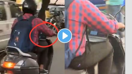 a man working on laptop while riding on a scooty