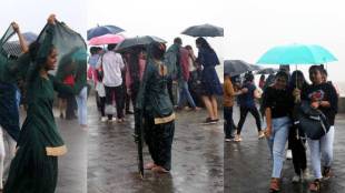 People holding umbrella enjoying amid rains, in Marin Drive, Mumbai