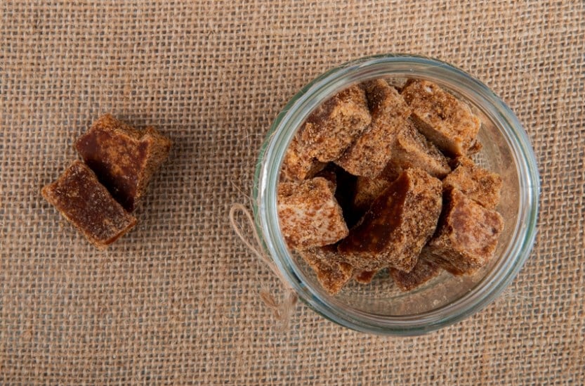 top view of palm sugar cubes in a glass jar on sackcloth texture background