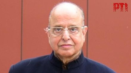 Portrait of Dr. K Kasturirangan, former ISRO chief, in front of a model satellite