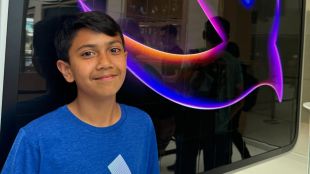 Teenage Indian coder showcasing SpendSmart app interface on smartphone