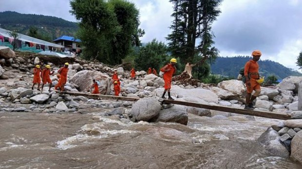 शुक्रवारी मंडी येथील सेराज खोऱ्यातील ढगफुटी झालेल्या भागात मदत आणि बचाव कार्य करत असताना एनडीआरएफचे जवान एका तात्पुरत्या पुलावरून चालत जातानाचे दृष्य. (एएनआय फोटो)
