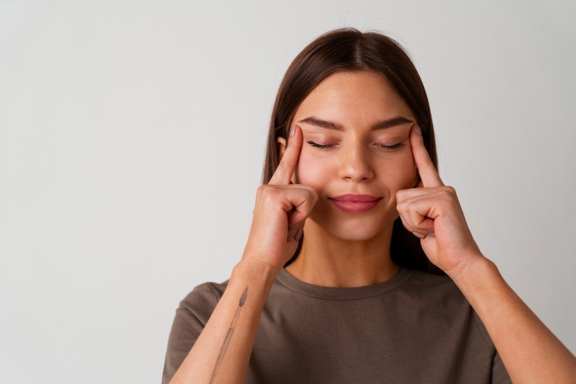 Portrait of young lady pressing fingers on puffy cheeks in tank top and looking funny front view
