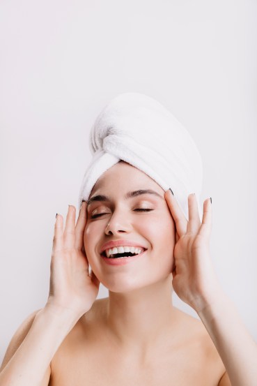 Positive lady enjoys morning spa treatment. Girl after shower posing on isolated background