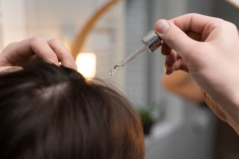 Woman hand holding her long hair with looking at damaged splitting ends of hair care problems