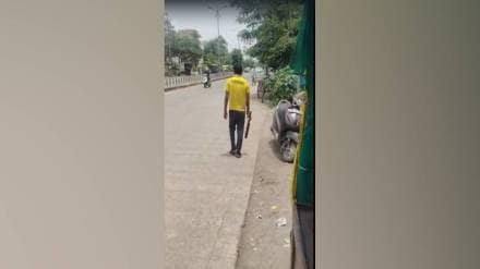 young man walking along cow protection road with sickle