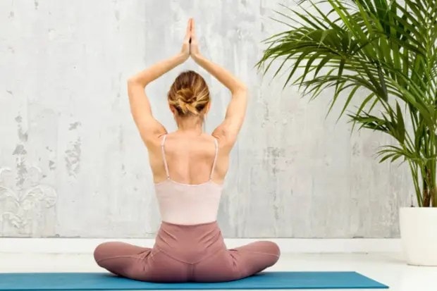 सीटेड हार्ट ओपनर (Seated heart opener) - या योगासनात, घसा, पोट आणि छाती ताणली जाते, जेणेकरून पेटके आणि सूज कमी होतील. (छायाचित्र स्रोत: कॅनव्हा)