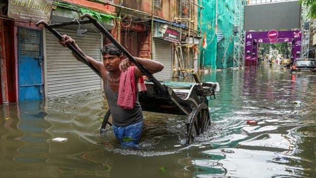 रात्रभर पडलेल्या पावसानंतर पाणी साचलेल्या भागातून एक माणूस हाताने रिक्षा ओढत आहे. (पीटीआय)