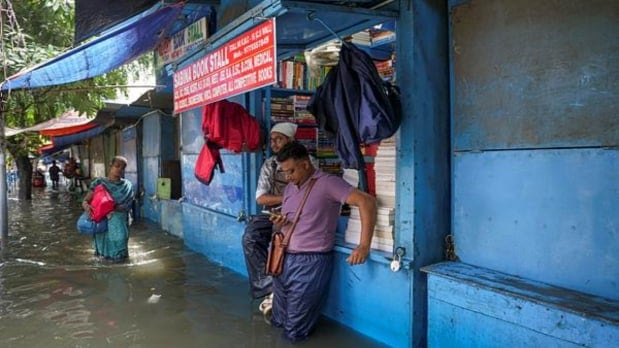 पावसामुळे कॉलेज स्ट्रीटवर पाणी साचले असताना लोक पुस्तकांच्या दुकानाजवळ उभे आहेत. (पीटीआय)