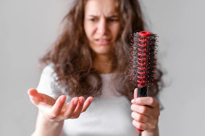 Woman washing hair with hot water affecting hair health and shine.
