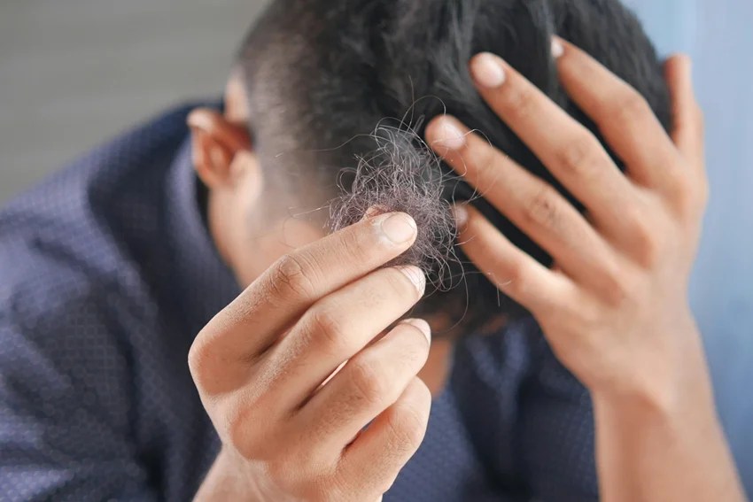 Woman washing hair with hot water affecting hair health and shine.
