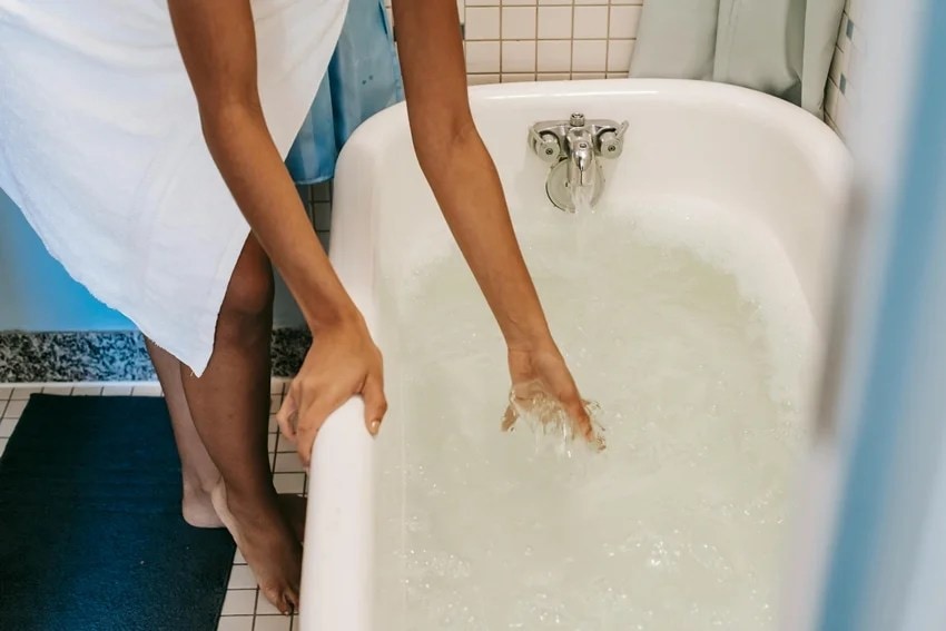 Woman washing hair with hot water affecting hair health and shine.