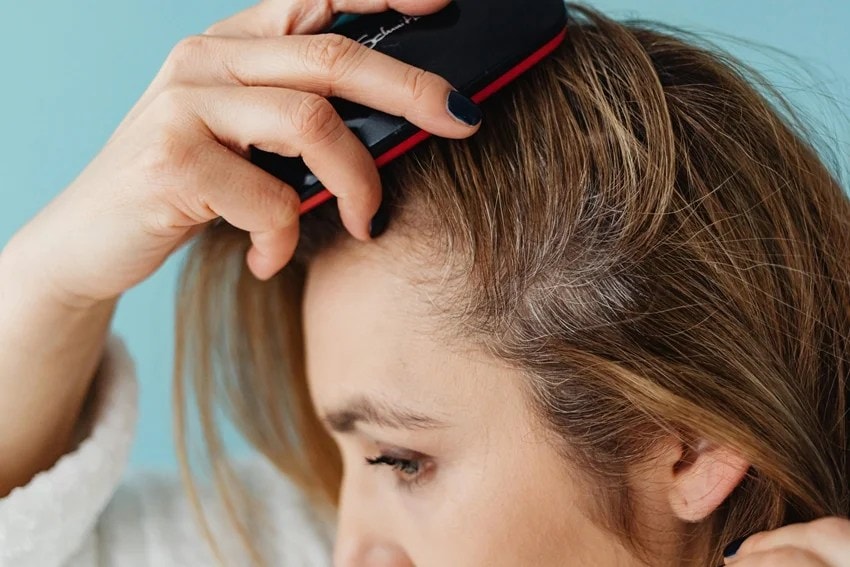 Woman washing hair with hot water affecting hair health and shine.