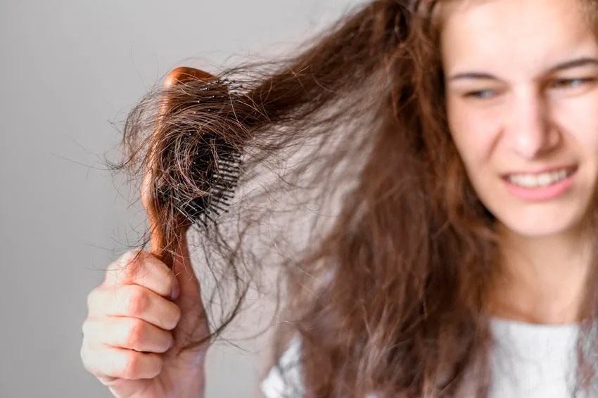 Woman washing hair with hot water affecting hair health and shine.