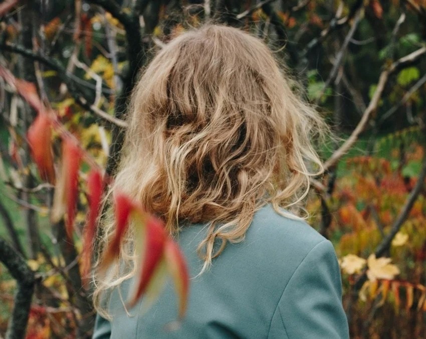 Woman washing hair with hot water affecting hair health and shine.