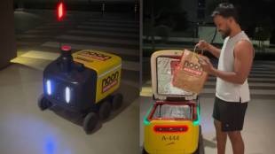 A small white autonomous food delivery robot moving on a pavement in Dubai, showcasing automated technology for door-to-door food service without human intervention.